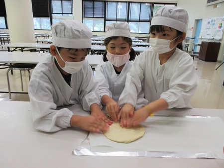 ピザ生地を伸ばす子どもたち